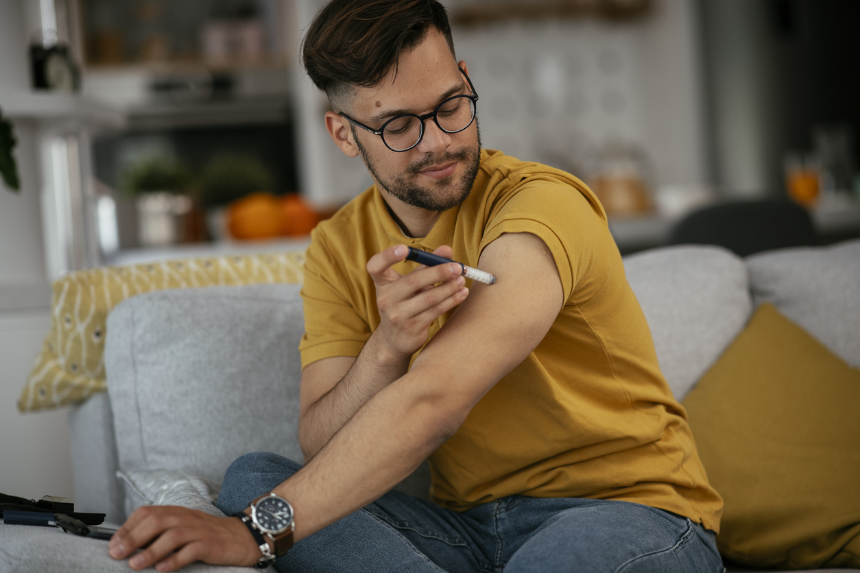 Young man giving himself a diabetes injection shot at home